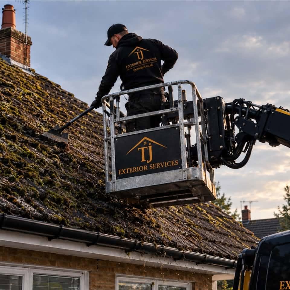 Taylor removing moss from a roof by hand from a cherry picker